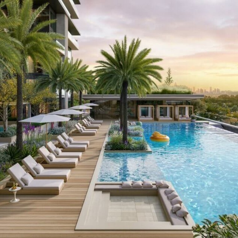 Pool deck at Ellington Villas Dubai — sun loungers and parasols along a timber deck beside an infinity pool at sunset