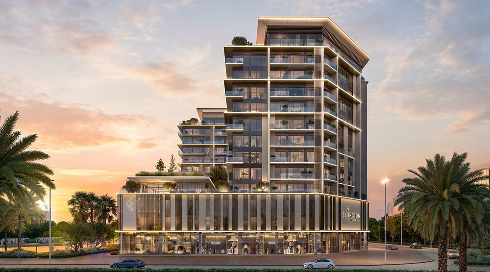 An Ellington Properties apartment building at dusk — stacked terraces with planting, illuminated horizontal banding and ground-floor retail